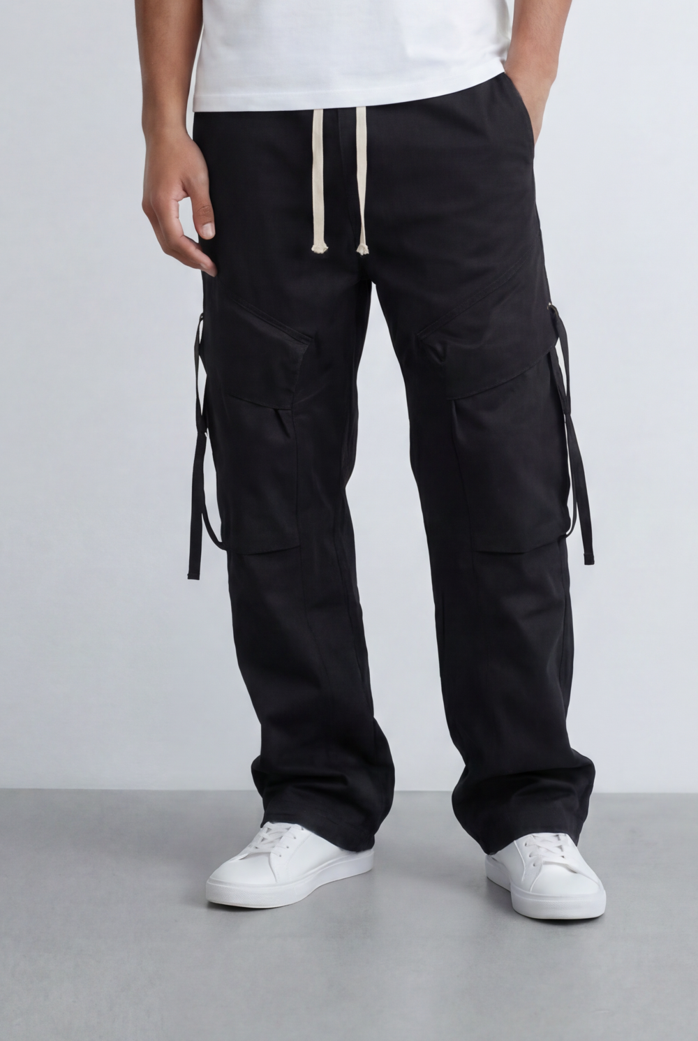 Men’s black utility cargo pants with waterproof flap pockets and cream drawstrings.