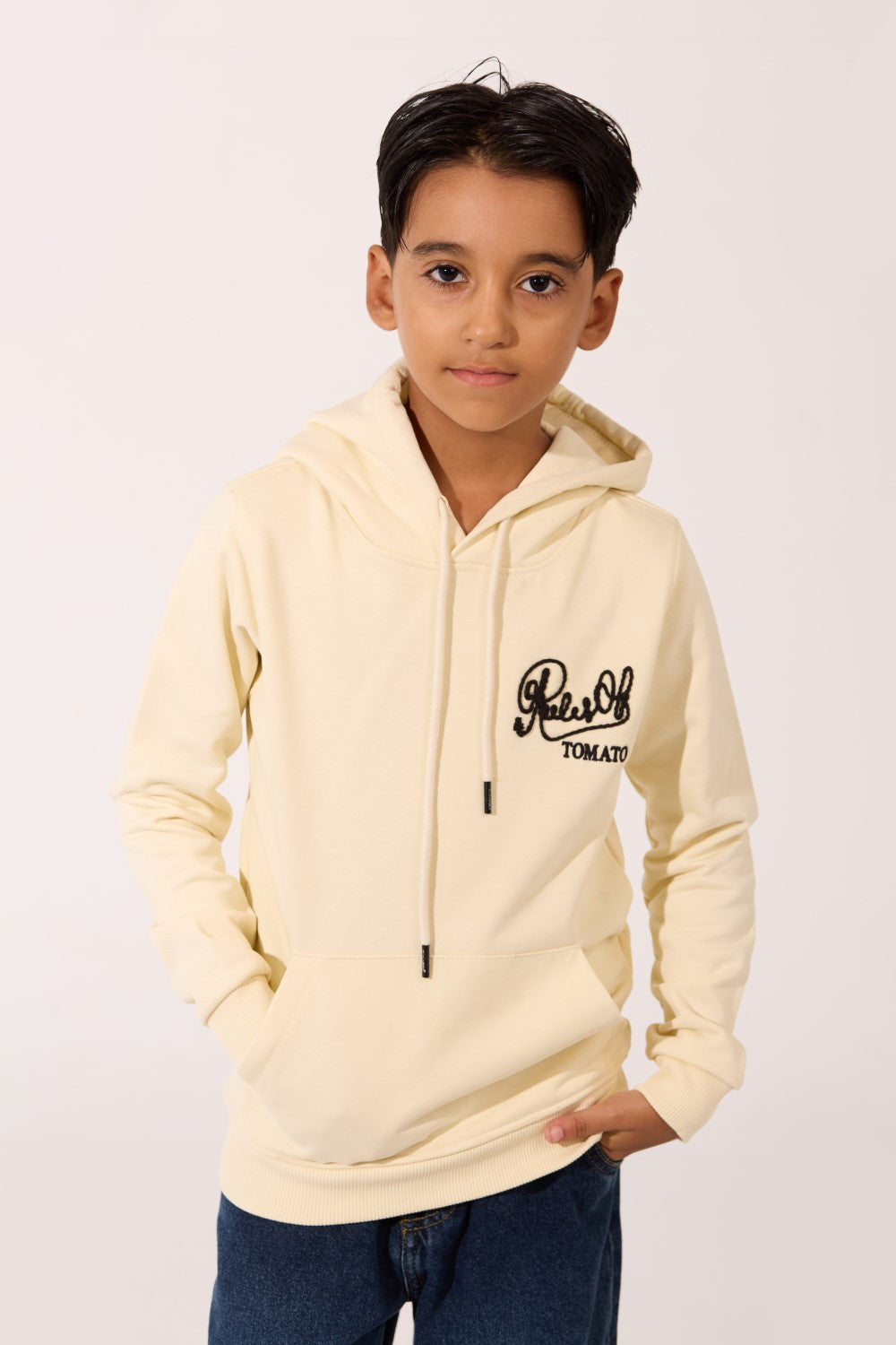 Boy's beige cotton hoodie with black script logo and front pocket by Tomato Store.
