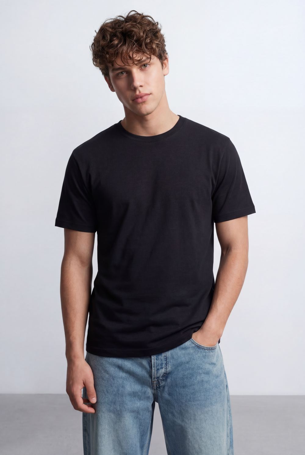 Man wearing a black Men’s Core Essential T-Shirt with a clean blank design and blue jeans.