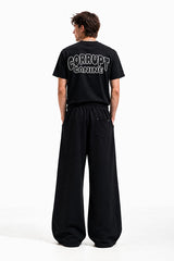 Man wearing black t-shirt with "CORRUPT CANINE" graphic and wide-leg black sweatpants.