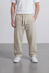 Men’s beige oversize sweatpants with minimal logo detail by tomato store, made of heavy cotton.