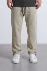 Men’s beige oversize sweatpants with embossed 'DREAM' side logo and white sneakers.