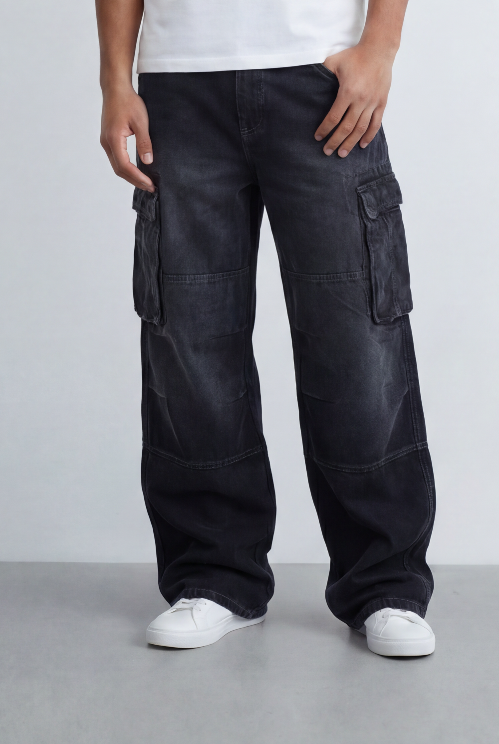 Men's black cargo jeans with utility pocket details and a relaxed fit, paired with white sneakers.