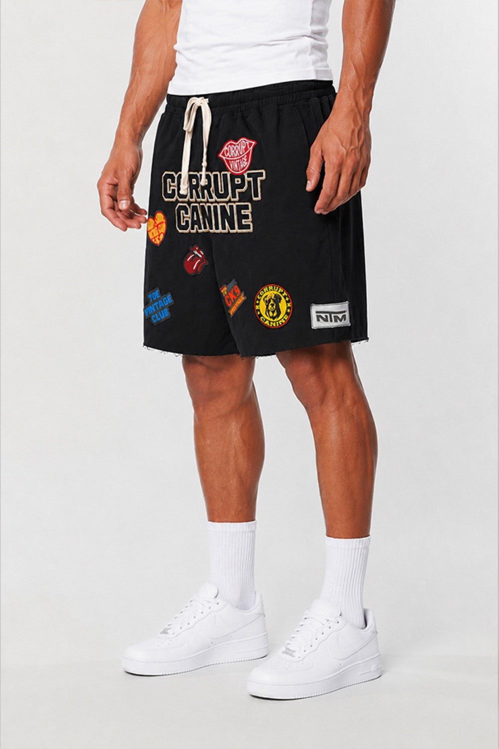 Person wearing black shorts with colorful patches on a white background