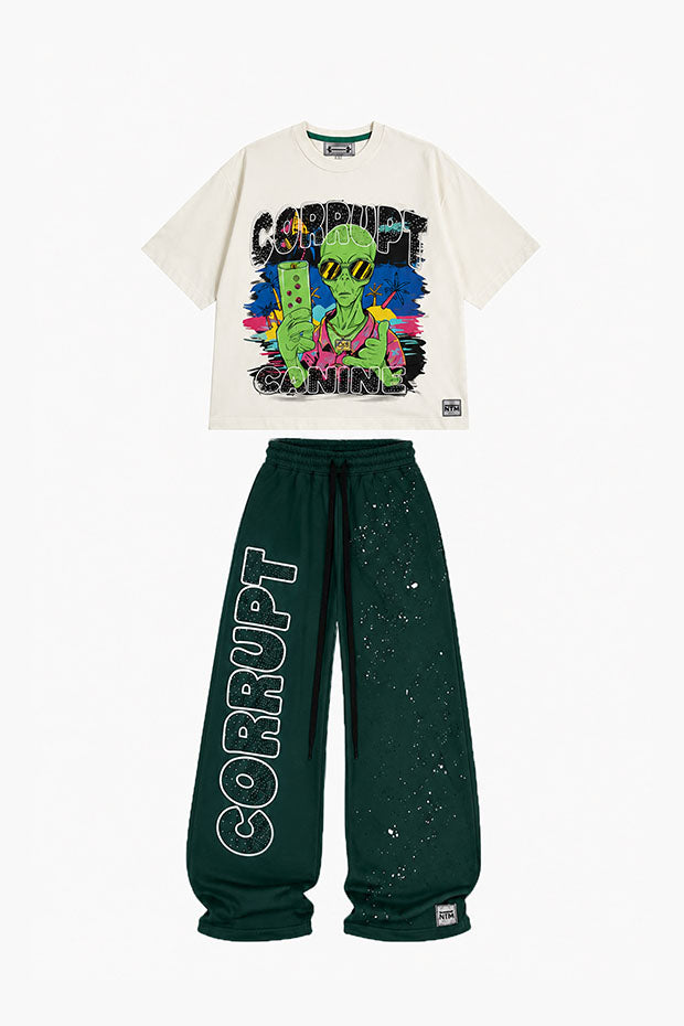 Cream graphic t-shirt with an alien playing a video game and green sweatpants with "CORRUPT" printed vertically.