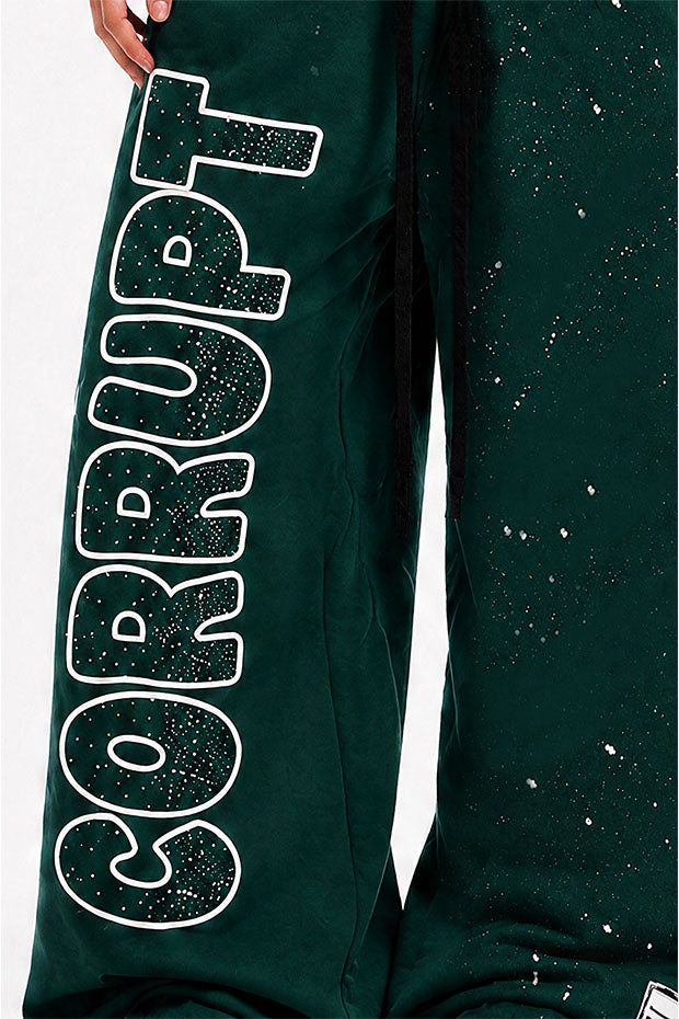 Green sweatpants with white outlined 'CORRUPT' graphic and paint splatter details.