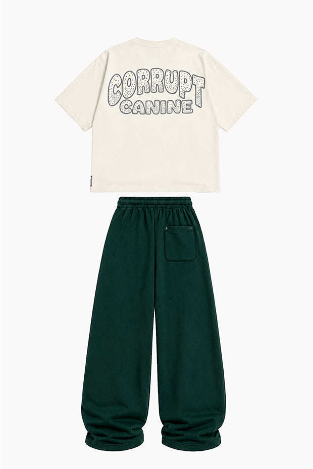 Cream graphic t-shirt with "CORRUPT CANINE" on the back and dark green wide-leg sweatpants with a back pocket.