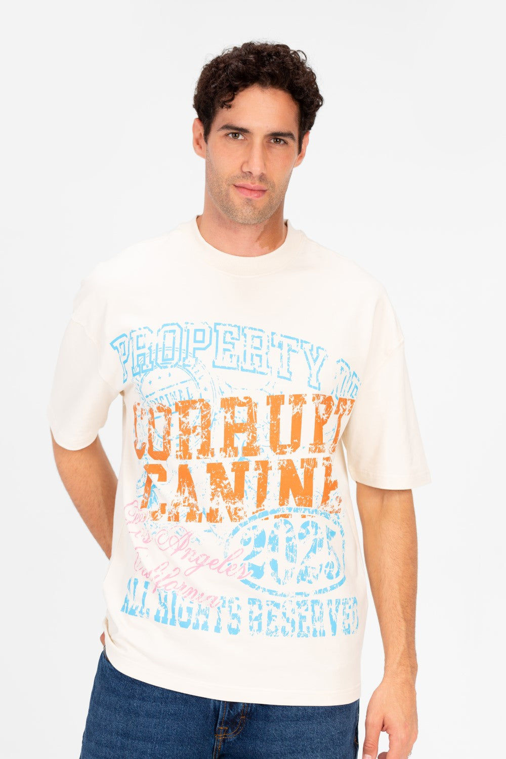 Man wearing an oversized cream t-shirt with distressed blue and orange graphic print.
